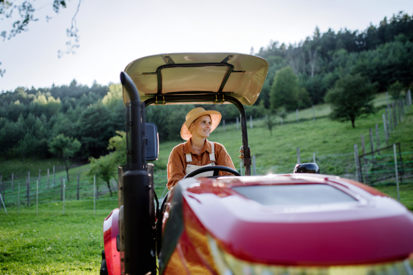 Progressive female farmer driving tractor on her own farm. Concept of women in agriculture.