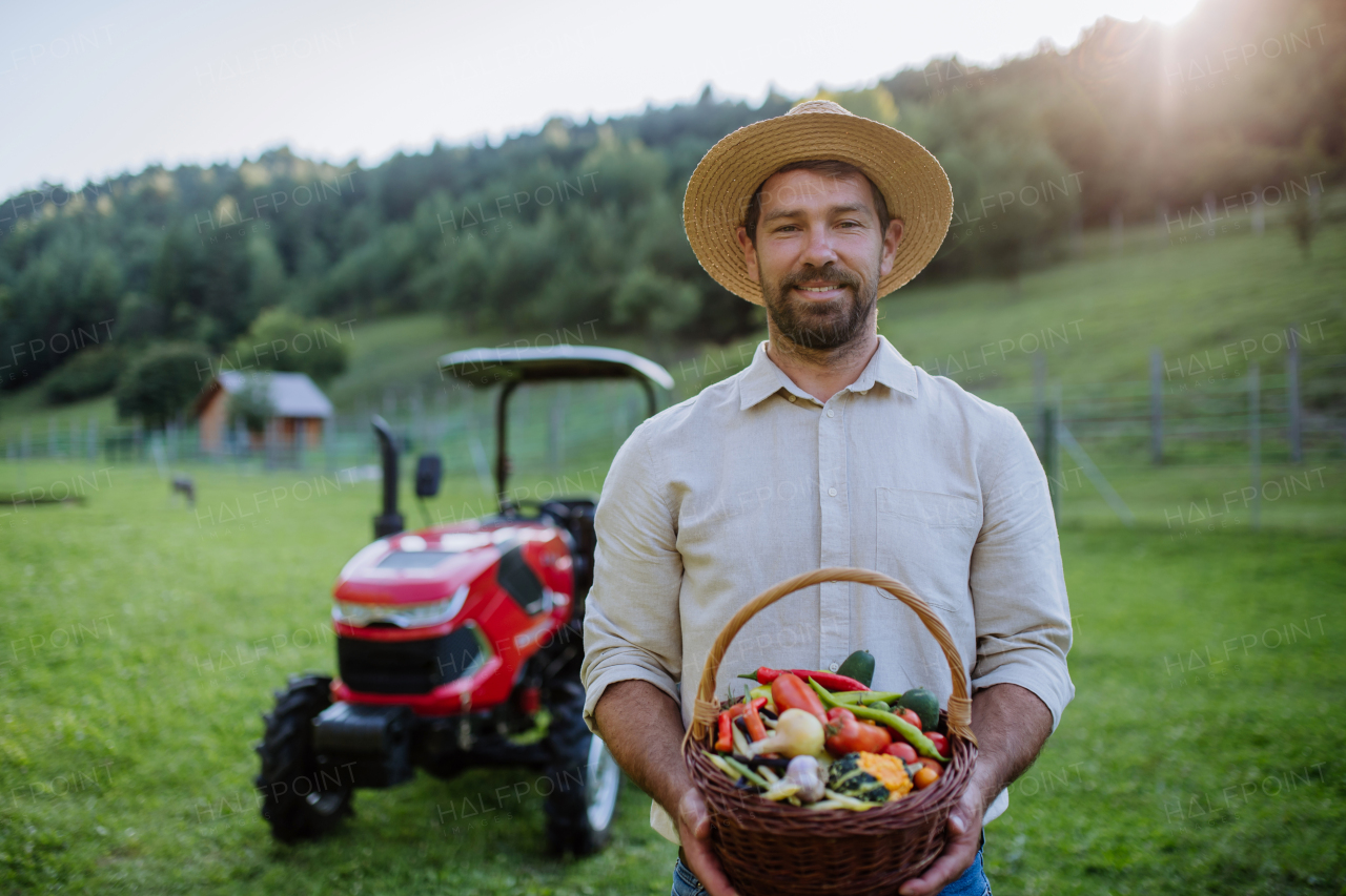 Portrait of farmer holding harvest basket full of fresh vegetables. Harvesting crops, collecting vegetables on family farm. Concept of multigenerational farming.