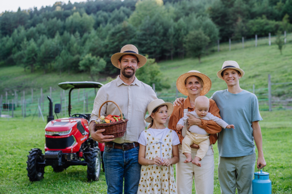 Portrait of farmer family holding harvest basket full of fresh vegetables. Harvesting crops, collecting vegetables on family farm. Concept of the multigenerational farming.