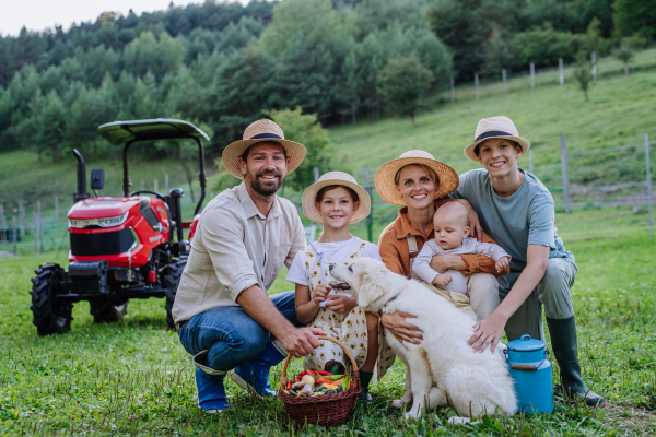 Portrait of farmer family holding harvest basket full of fresh vegetables. Harvesting crops, collecting vegetables on family farm. Concept of the multigenerational farming.