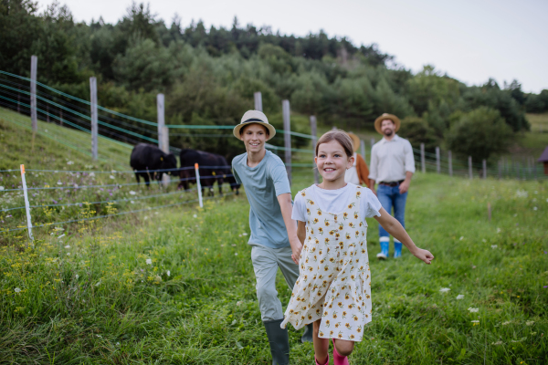 Children from farmer family running on farm, holding hands, having fun. Concept of multigenerational farming.