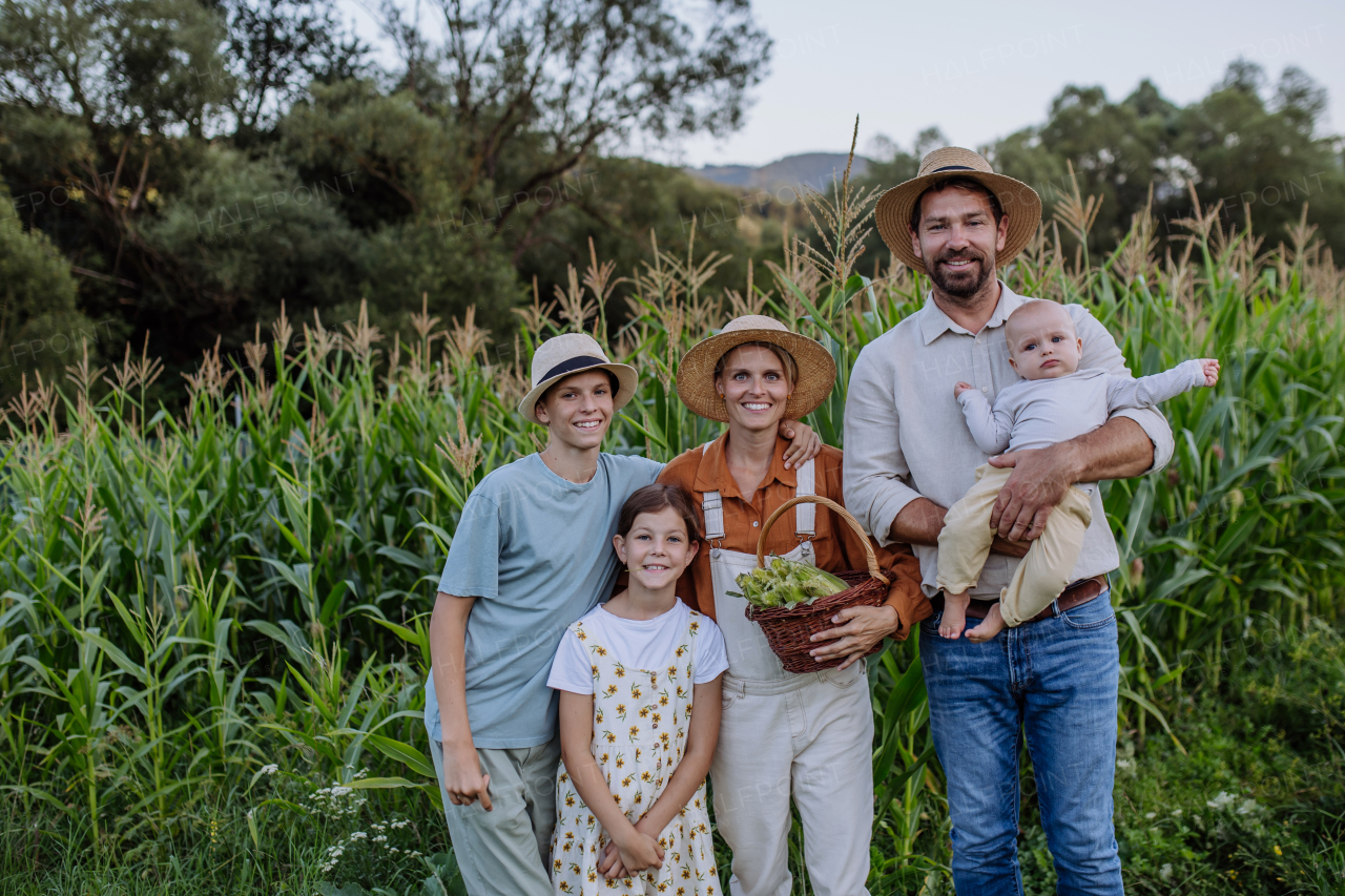 Farmer family standign in front of field with corns. Concept of multigenerational and family farming.