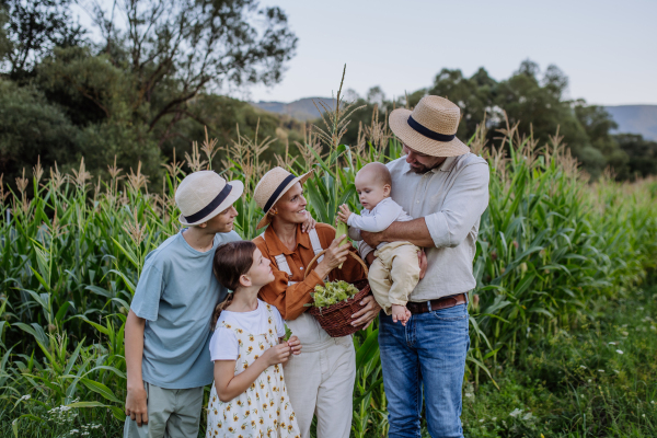 Farmer family standign in front of field with corns. Concept of multigenerational and family farming.