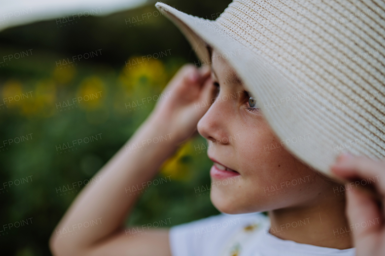 Beautiful young girl standing in front of sunflowers on the field. Girl enjoying a beautiful flowers in the summer farm fields. Future female farmer.