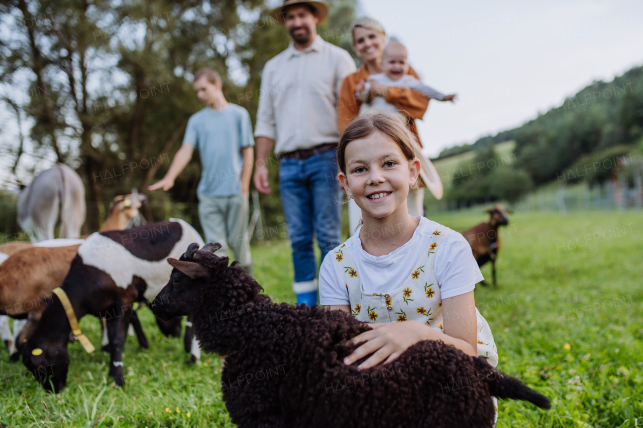 Portrait of farmer family petting donkey and goats on their farm. A gray mule and goats as a farm animals at the family farm. Concept of multigenerational farming.