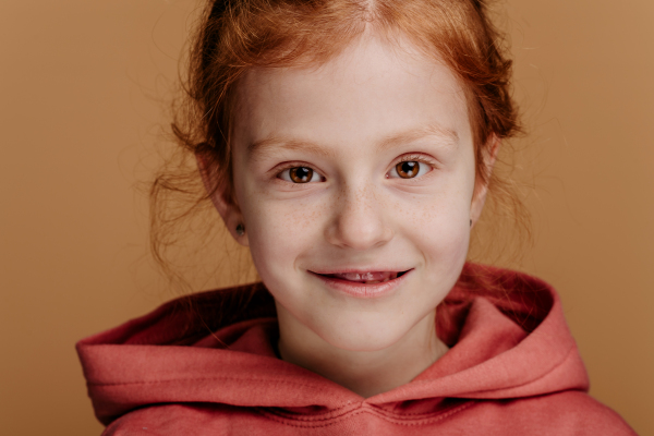 Portrait of little redhead girl in hoodie, studio shoot.