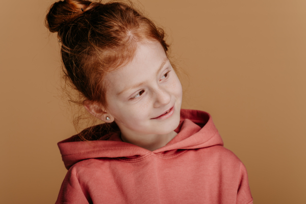 Portrait of little redhead girl in hoodie, studio shoot.