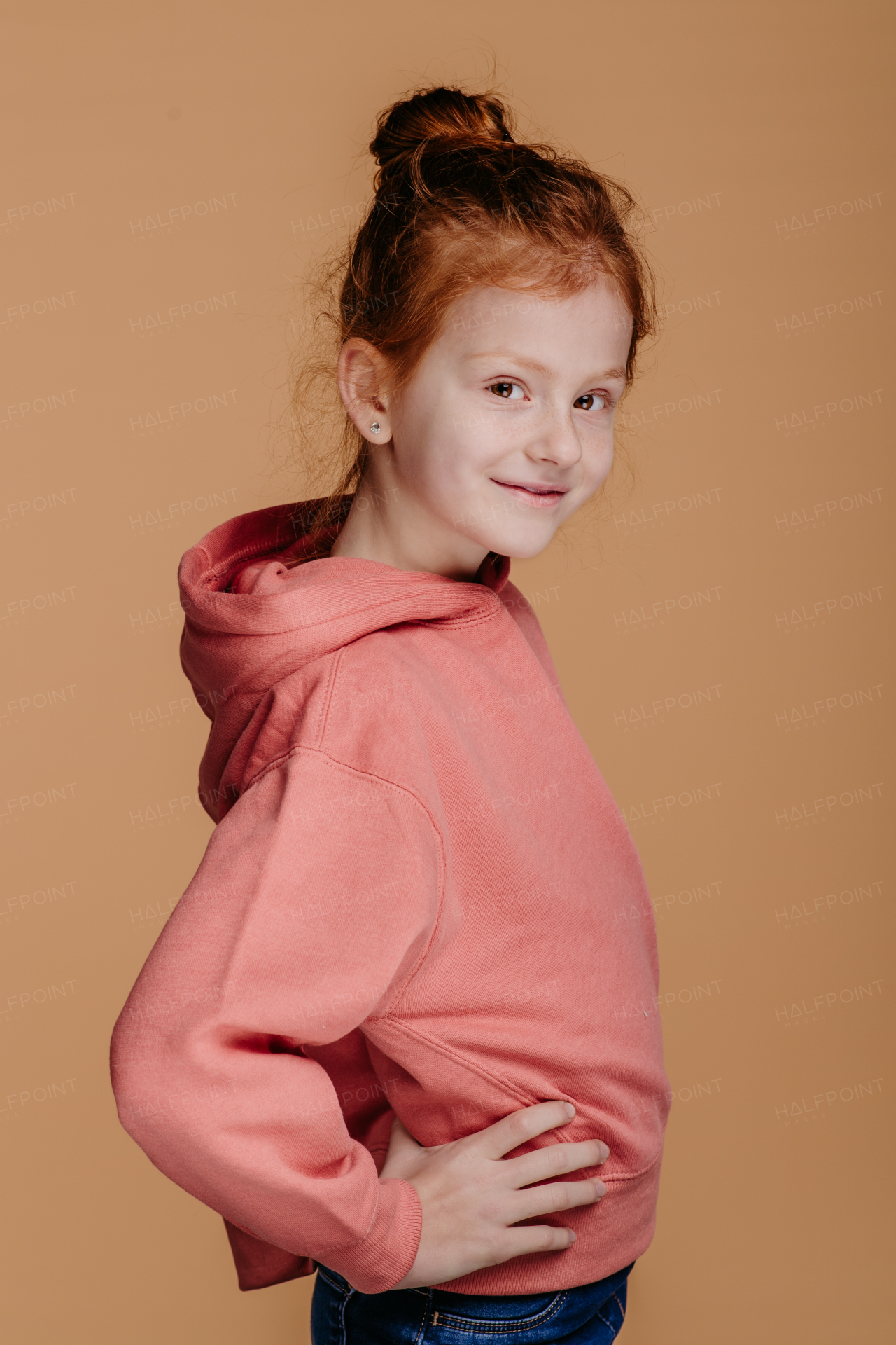 Portrait of little redhead girl in hoodie, studio shoot.