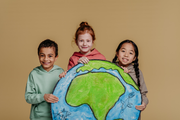 Portrait of three children with model of Earth, studio shoot. Concept of diversity in a friendship.