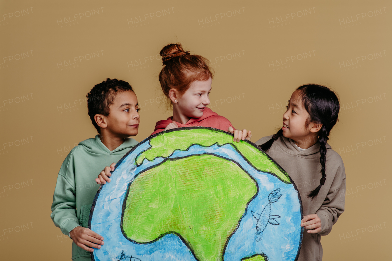 Portrait of three children with model of Earth, studio shoot. Concept of diversity in a friendship.