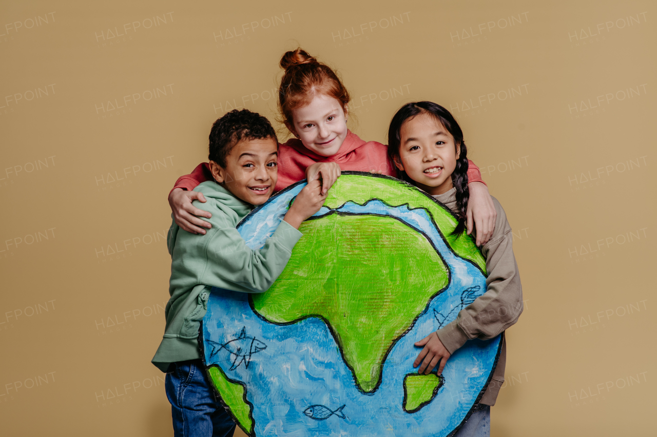 Portrait of three children with model of Earth, studio shoot. Concept of diversity in a friendship.