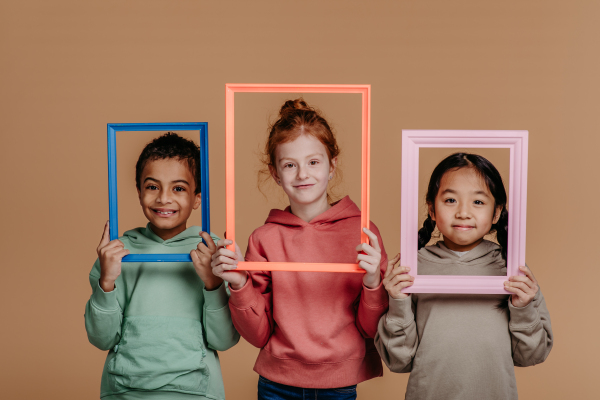 Portrait of three children with frames, studio shoot. Concept of diversity in a friendship.