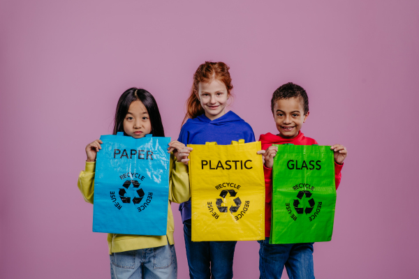 Portrait of three children posing with bins for separated rubbish.