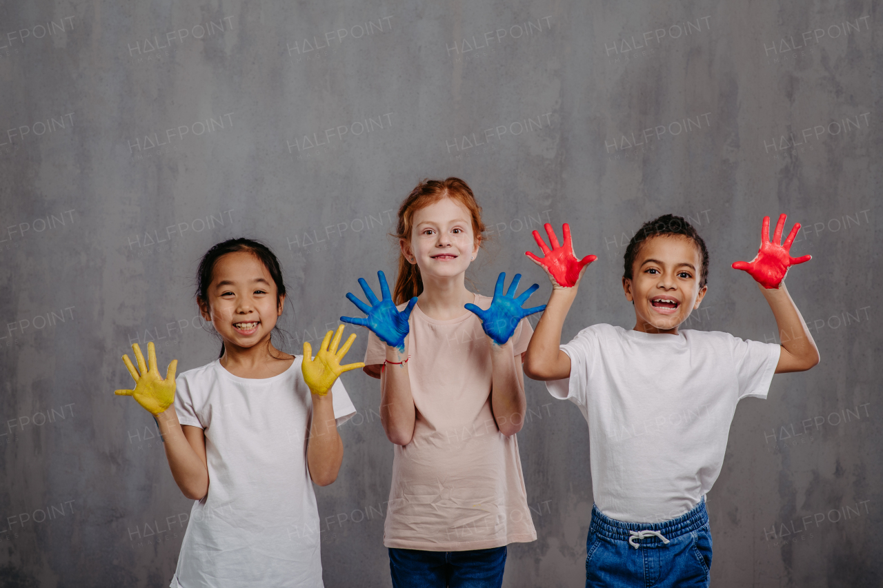 Portrait of happy kids with painted hands, studio shoot.