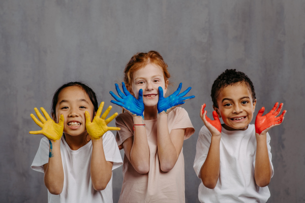 Portrait of happy kids with painted hands, studio shoot.