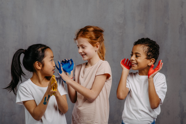 Portrait of happy kids with painted hands, studio shoot.