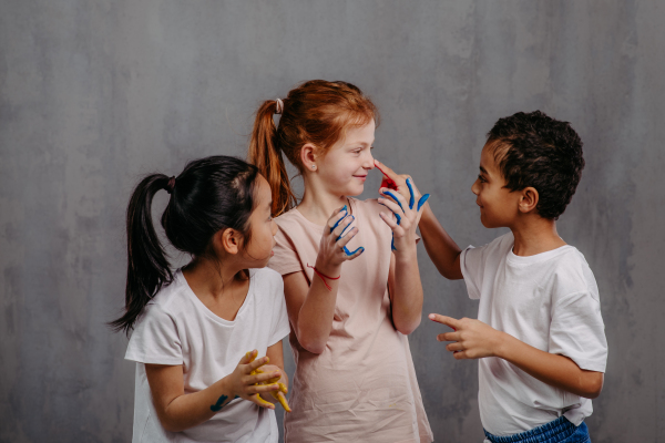 Portrait of happy kids with finger colours and painted t-shirts.