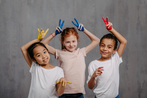 Portrait of happy kids with painted hands, studio shoot.