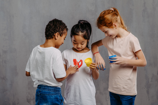 Portrait of happy kids with painted hands, studio shoot.