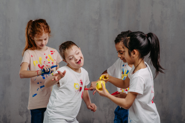 Happy kids with finger colours painting t-shirts.