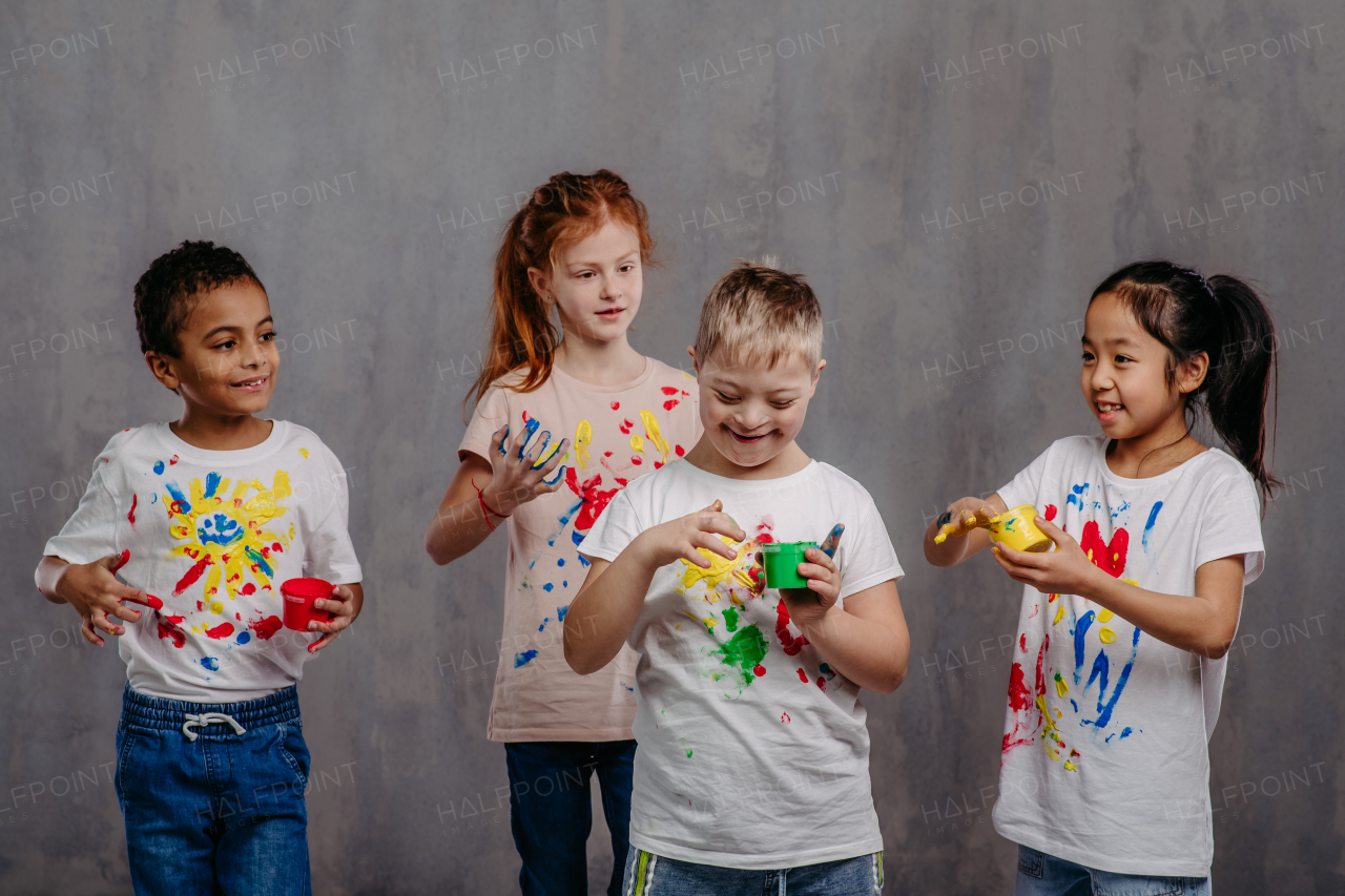 Portrait of happy kids with finger colours and painted t-shirts.