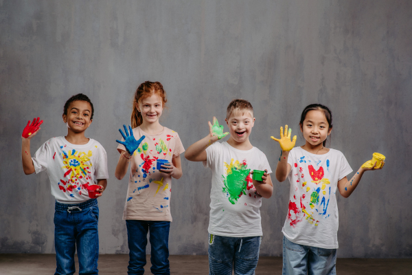 Portrait of happy kids with finger colours and painted t-shirts.