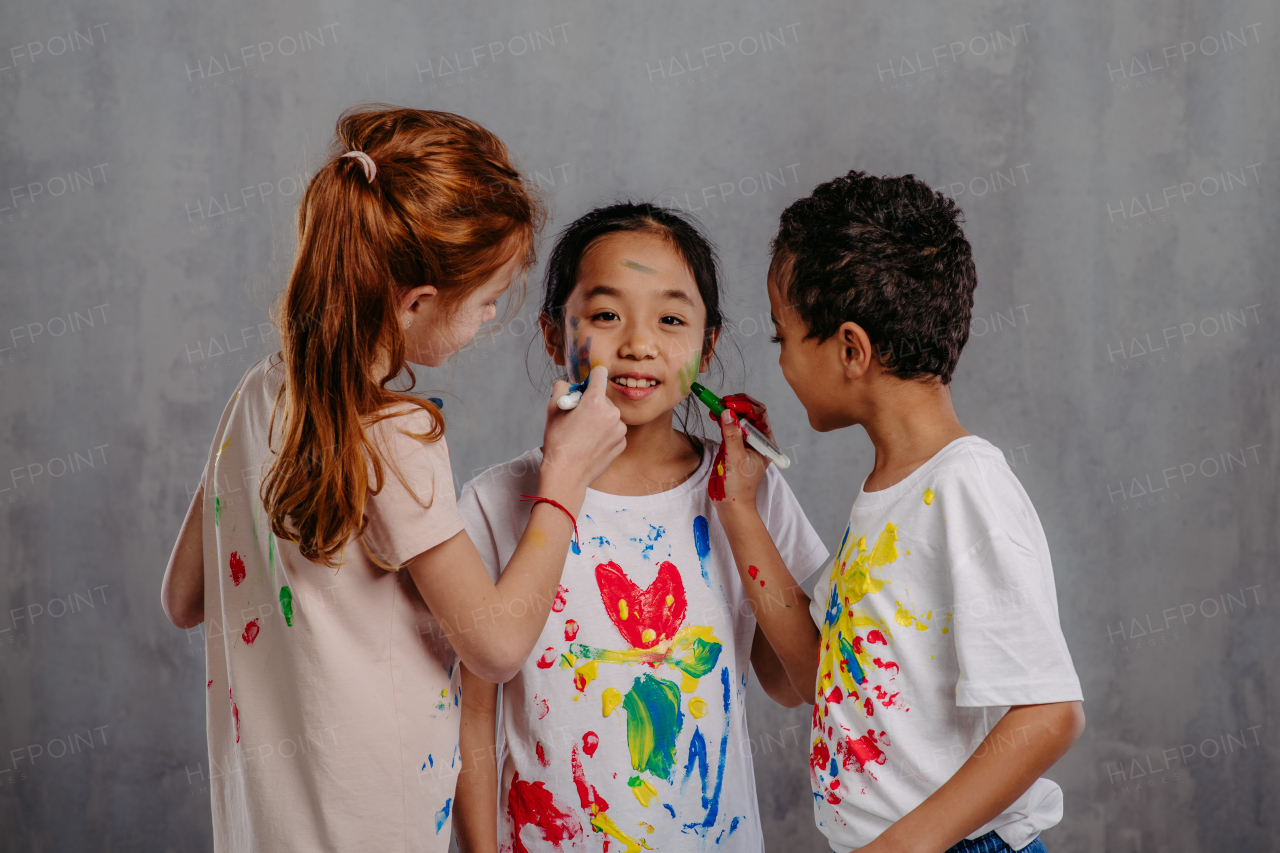 Portrait of happy kids with finger colours and painted t-shirts.