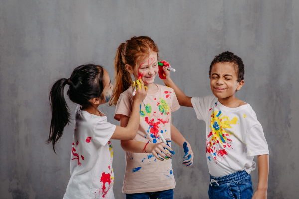 Portrait of happy kids with finger colours and painted t-shirts.