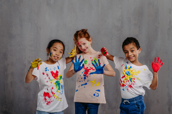 Portrait of happy kids with finger colours and painted t-shirts.