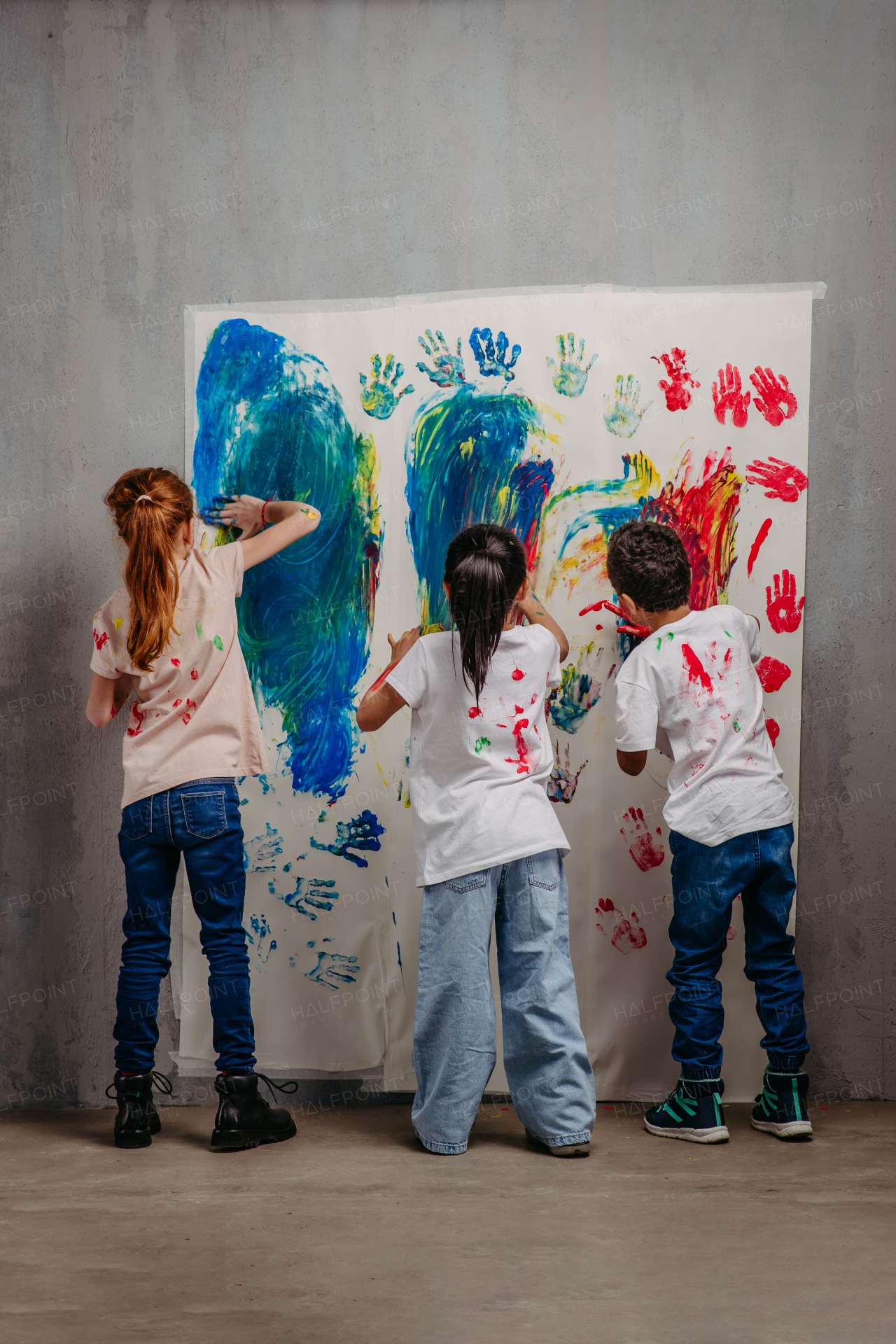 Rear view of happy kids with finger colours and painted t-shirts.