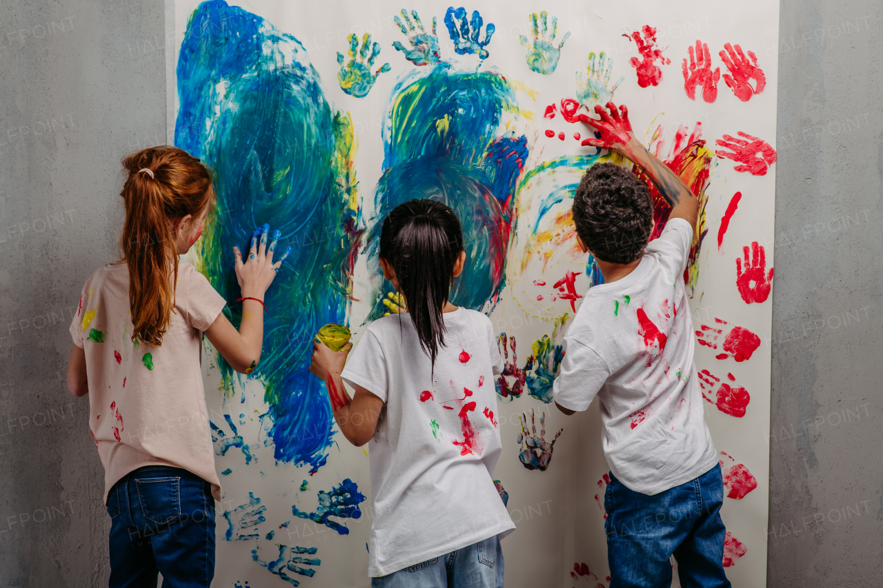 Rear view of happy kids with finger colours and painted t-shirts.