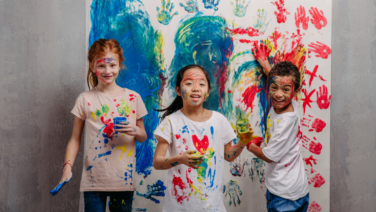 Portrait of happy kids with finger colours and painted t-shirts.