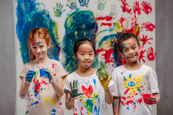 Portrait of happy kids with finger colours and painted t-shirts.