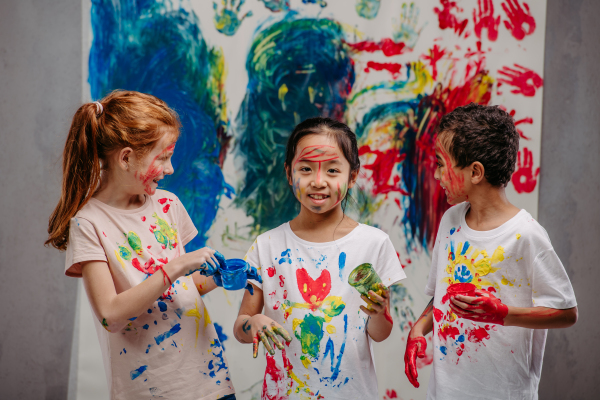 Portrait of happy kids with finger colours and painted t-shirts.