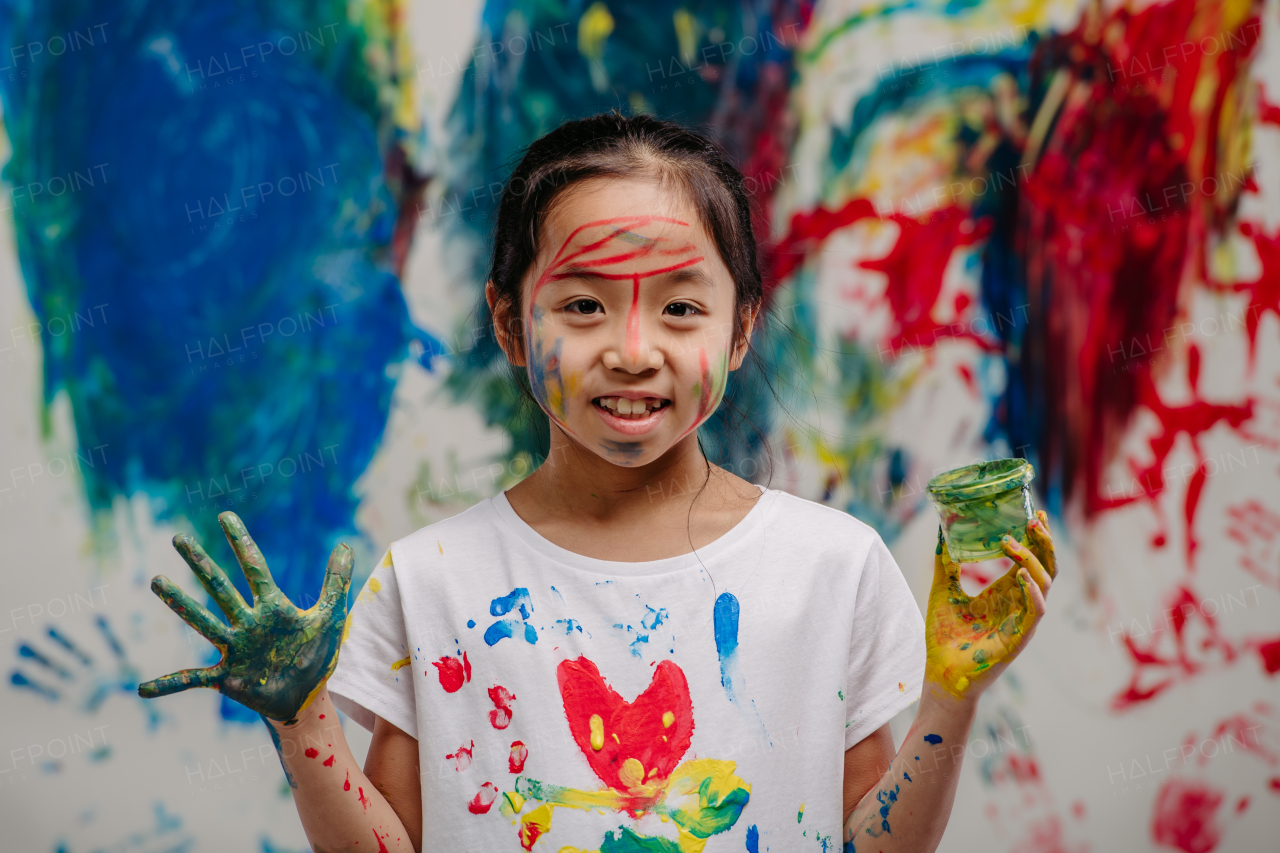 Portrait of happy kid with finger colours and painted t-shirts.