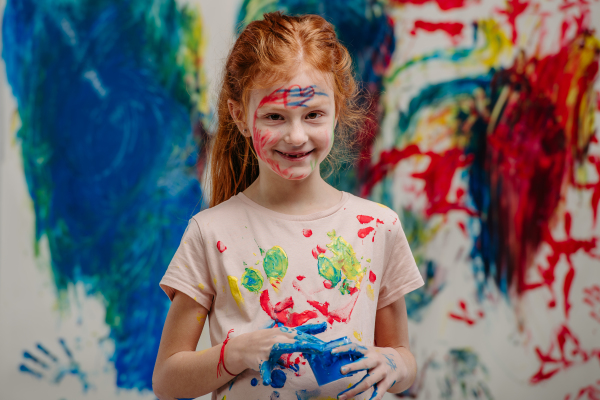 Portrait of happy kid with finger colours and painted t-shirts.