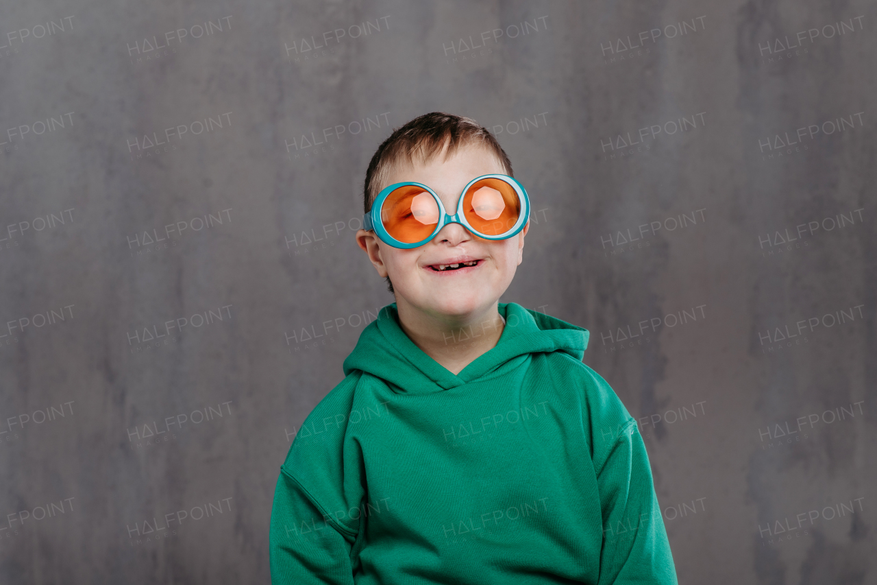 Funny portrait of a little boy with down syndrome, studio shoot.