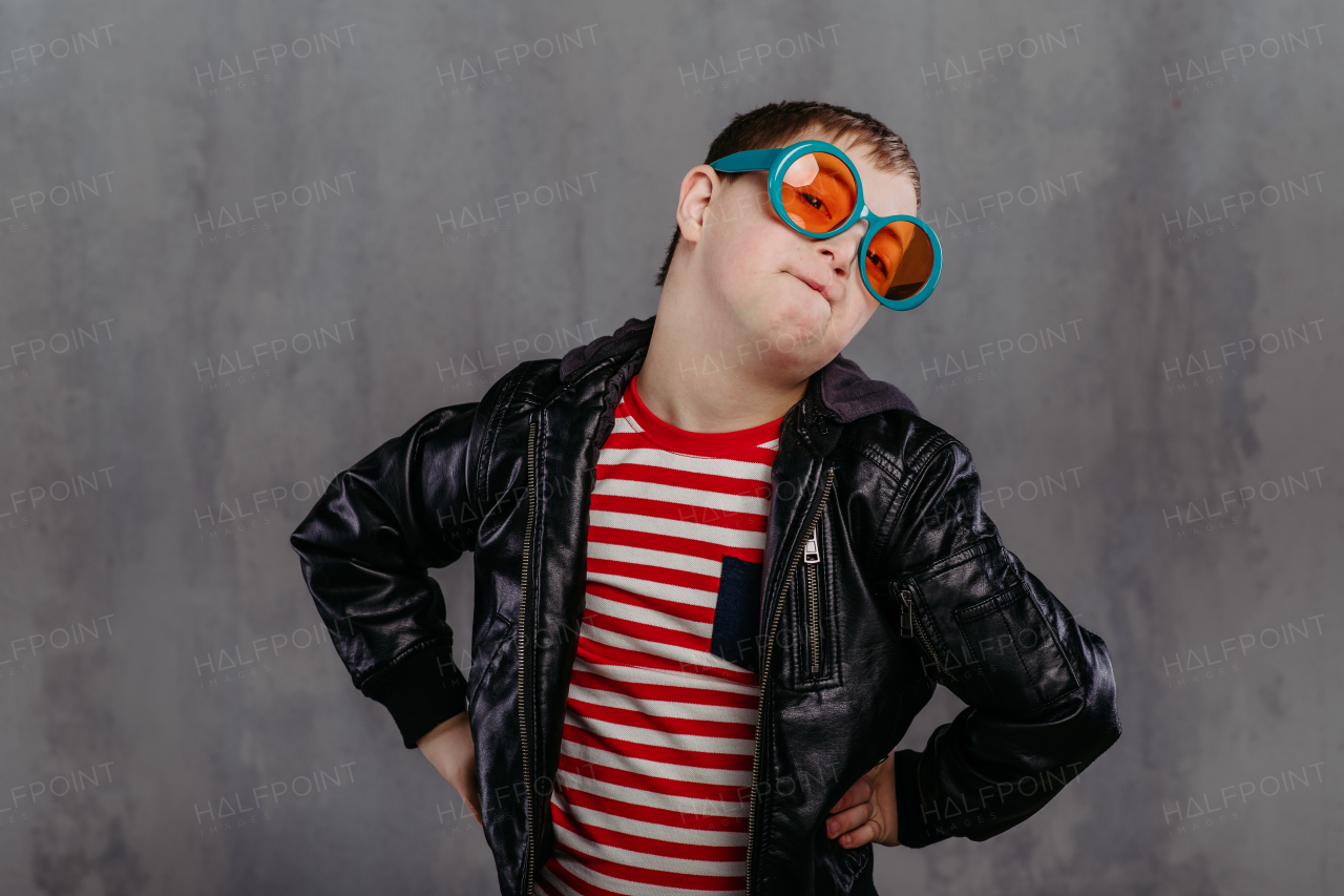 Funny portrait of a little boy with down syndrome, studio shoot.