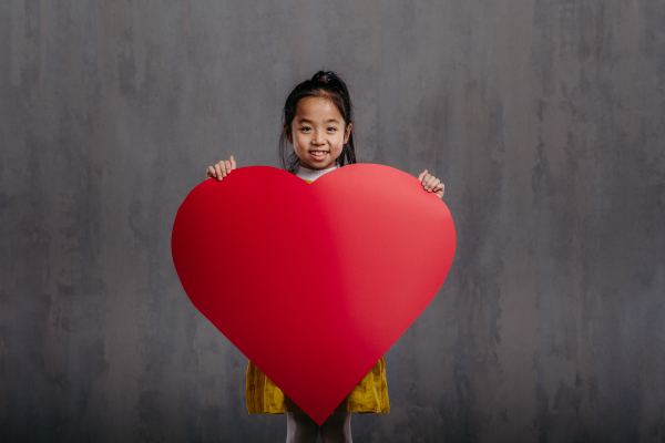 Little girl holding paper heart, studio photography.