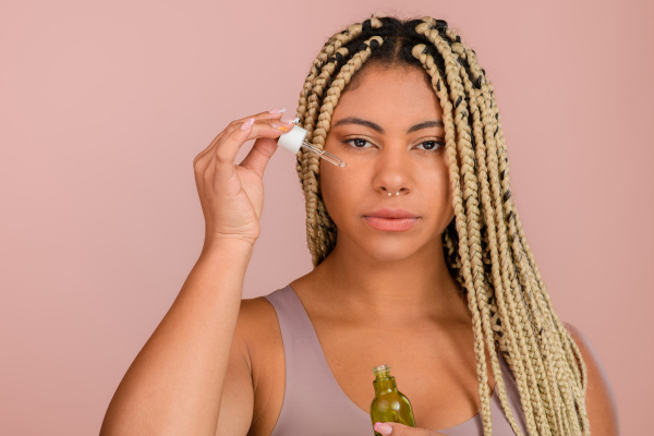 Portrait of young woman holding skincare serum drops in bottle.Concept of beauty and skincare.