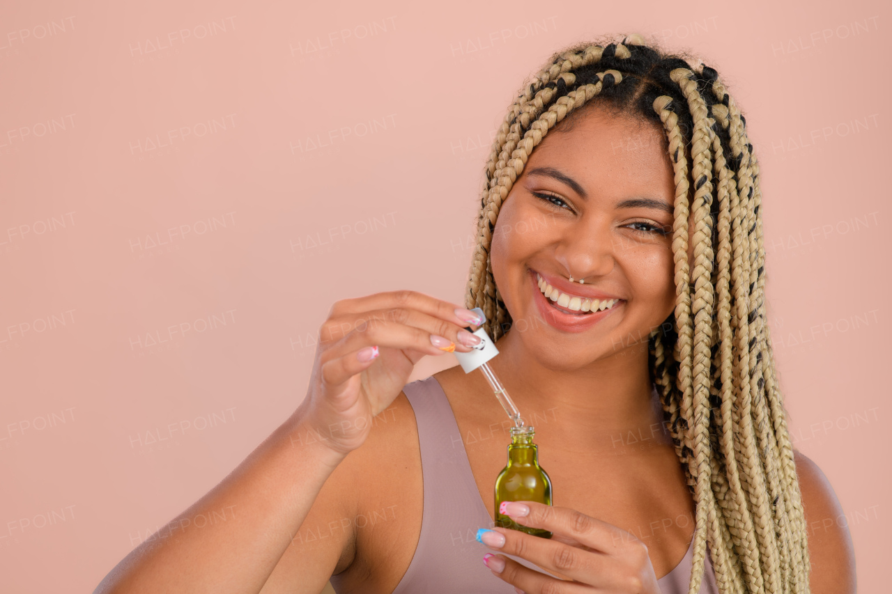 Portrait of young woman holding skincare serum drops in bottle.Concept of beauty and skincare.