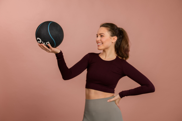 Portrait of young woman in sportive clothes with a medicimbal.