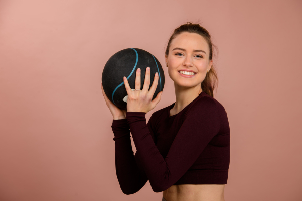 Portrait of young woman in sportive clothes with a medicimbal.