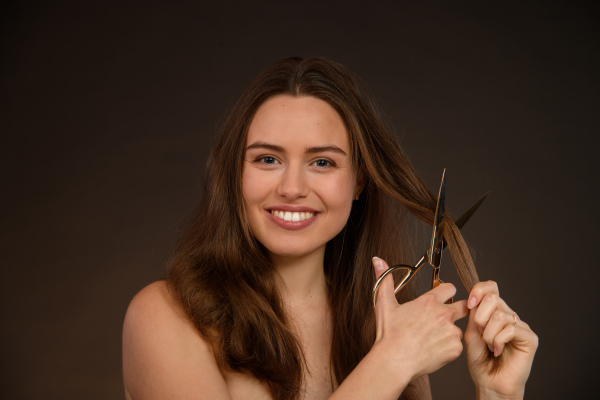 Portrait of young woman cutting hair, cancer solidarity concept.