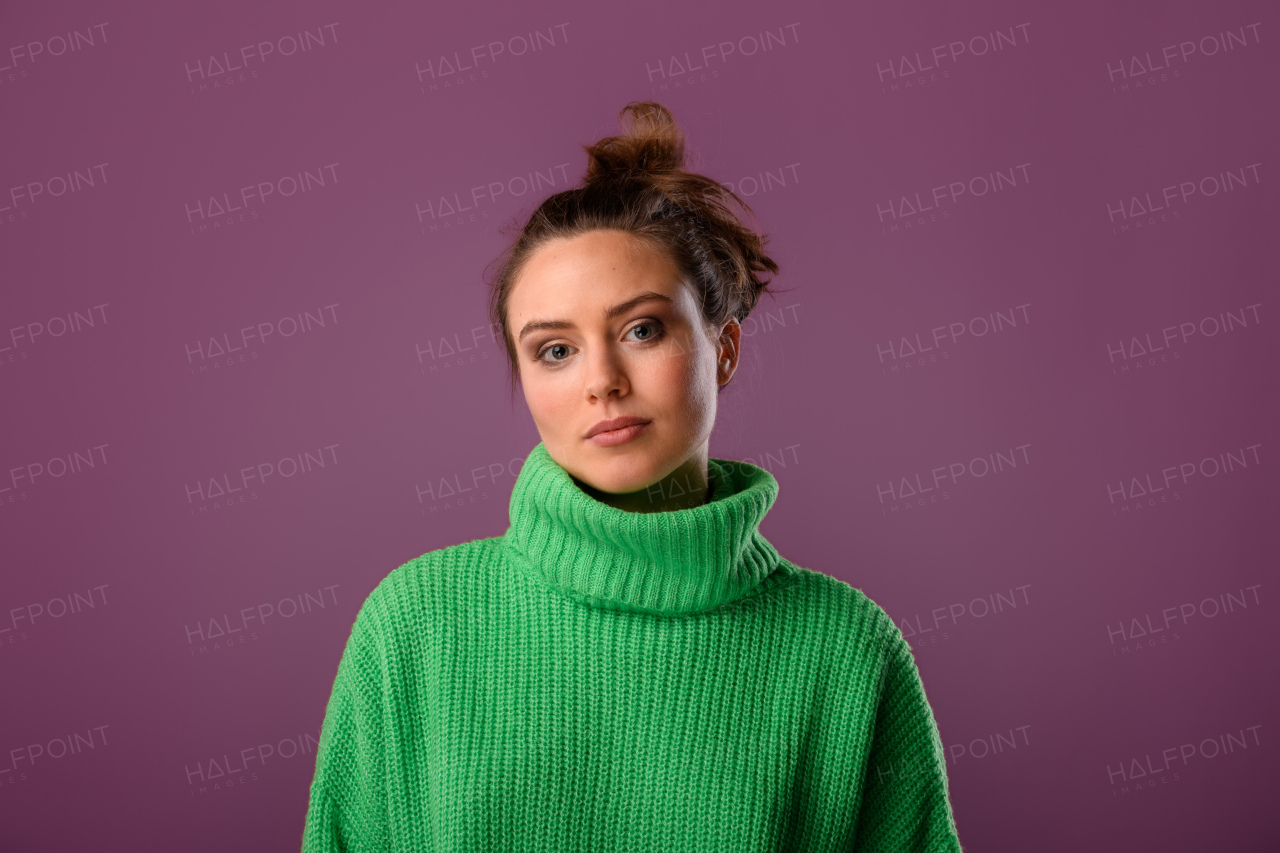 Young caucasian woman posing in sweater during studio shooting.