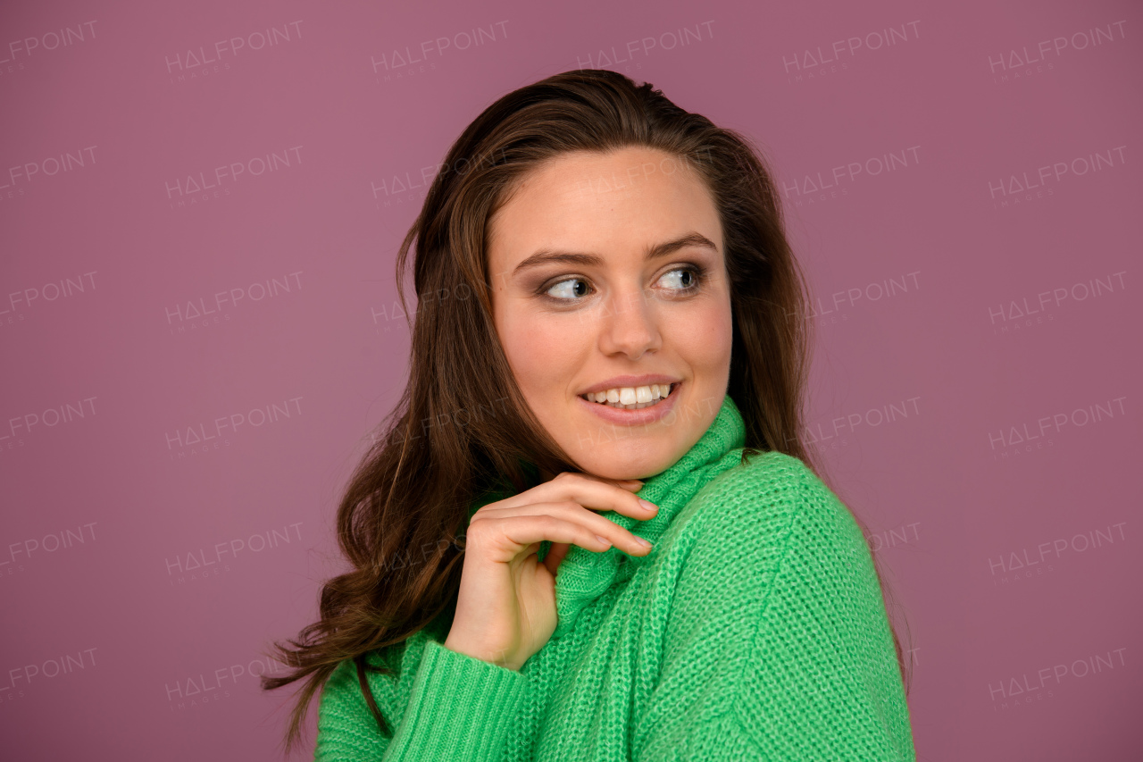 Young happy woman posing in sweater during studio shooting.