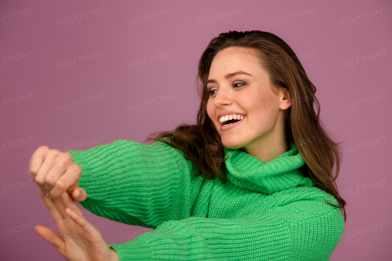 Young happy woman posing in sweater during studio shooting.