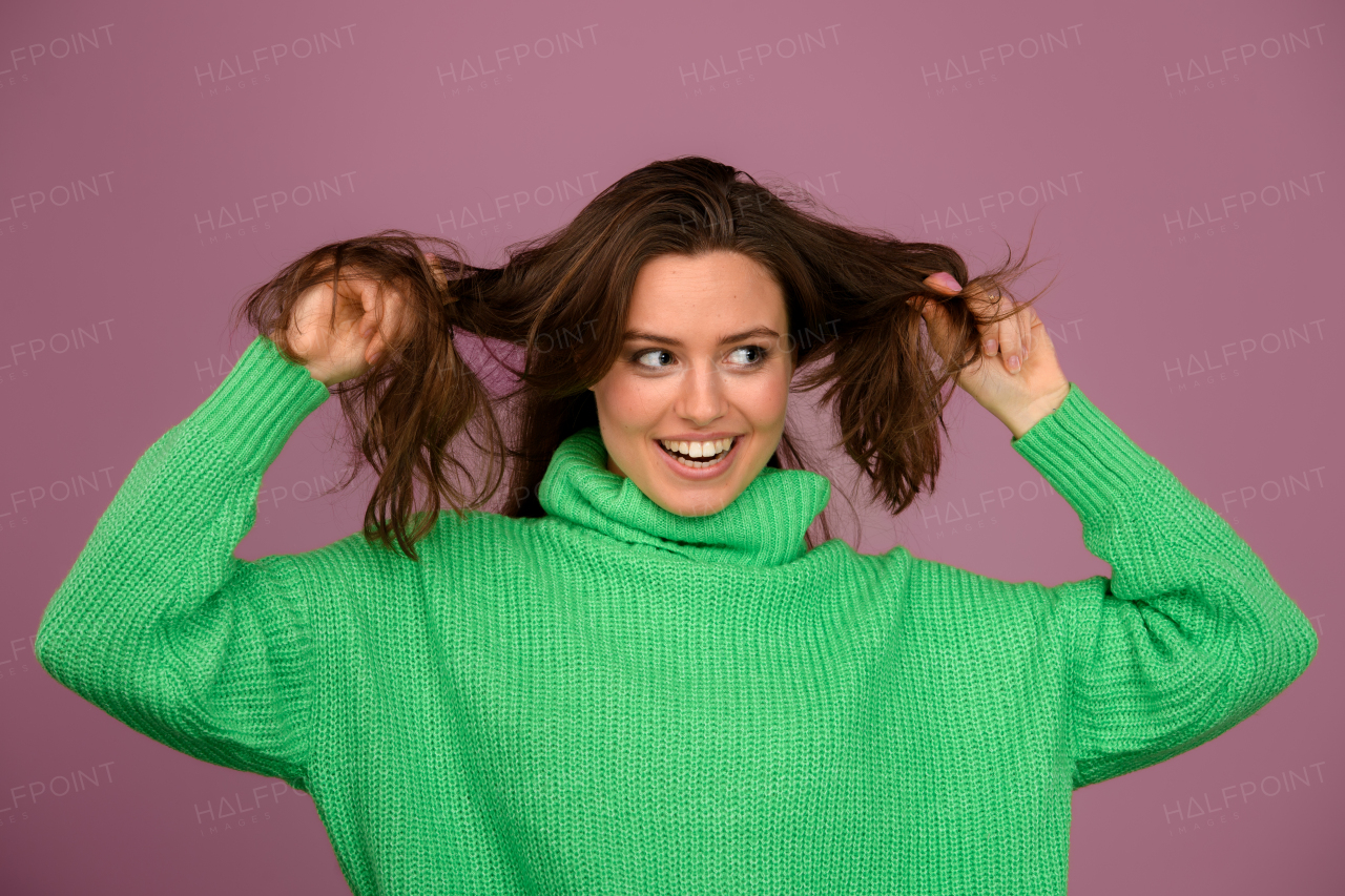 Young happy woman posing in sweater during studio shooting.