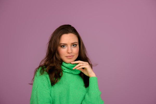 Young happy woman posing in sweater during studio shooting.