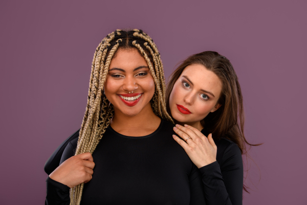 Two happy multiracial friends hugging and smiling.